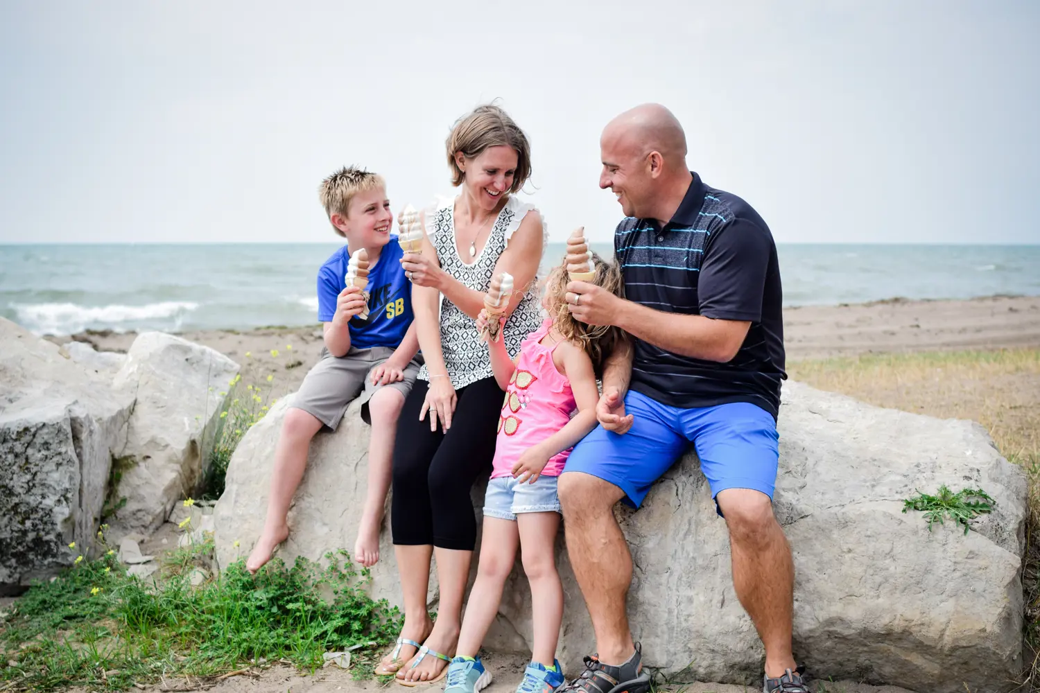 family sitting on rock enjoying ice cream