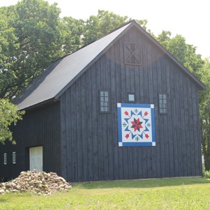 grey barn with a patterned quilt during the day